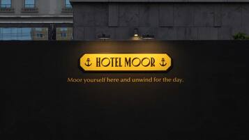 Placa de hotel com o nome 'HOTEL MOOR' e o slogan 'Ancore-se aqui e relaxe o dia todo'.