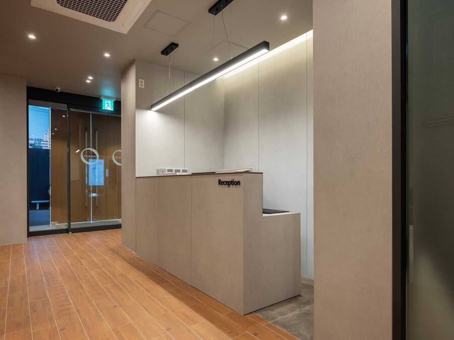 A reception area with a reception desk labeled "Reception," a glass door entrance, and a wooden floor.