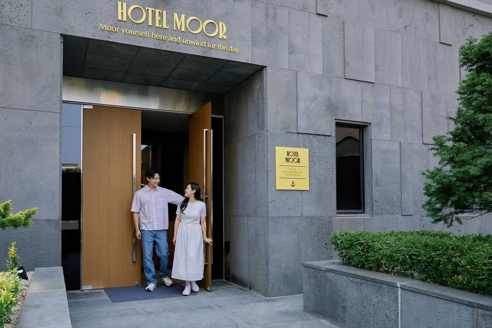 Entrada de hotel con un letrero que dice 'HOTEL MOOR' y un mensaje de bienvenida.