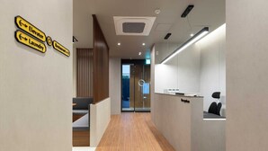 A modern reception area with a reception desk, a seating area, and directional signs for elevator, laundry, and restaurant. - Moor Hotel by Anook Mokpo (Mokpo)