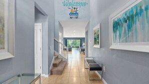 A modern hallway with a 'Welcome' sign featuring Mickey and Minnie Mouse, a staircase, and a glass railing. - 8BR Villa! Free Arcade, Pool, Spa Windsor Westside (Kissimmee)