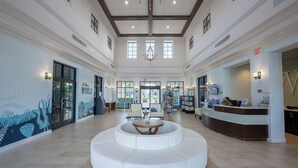 A spacious lobby with a central seating area, a reception desk, and a chandelier. - 8BR Villa! Free Arcade, Pool, Spa Windsor Westside (Kissimmee)