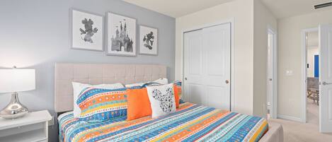 A bedroom with a bed, a nightstand, a door, and wall art.
