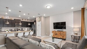 A modern living room with a sofa, armchairs, a coffee table, and a TV.