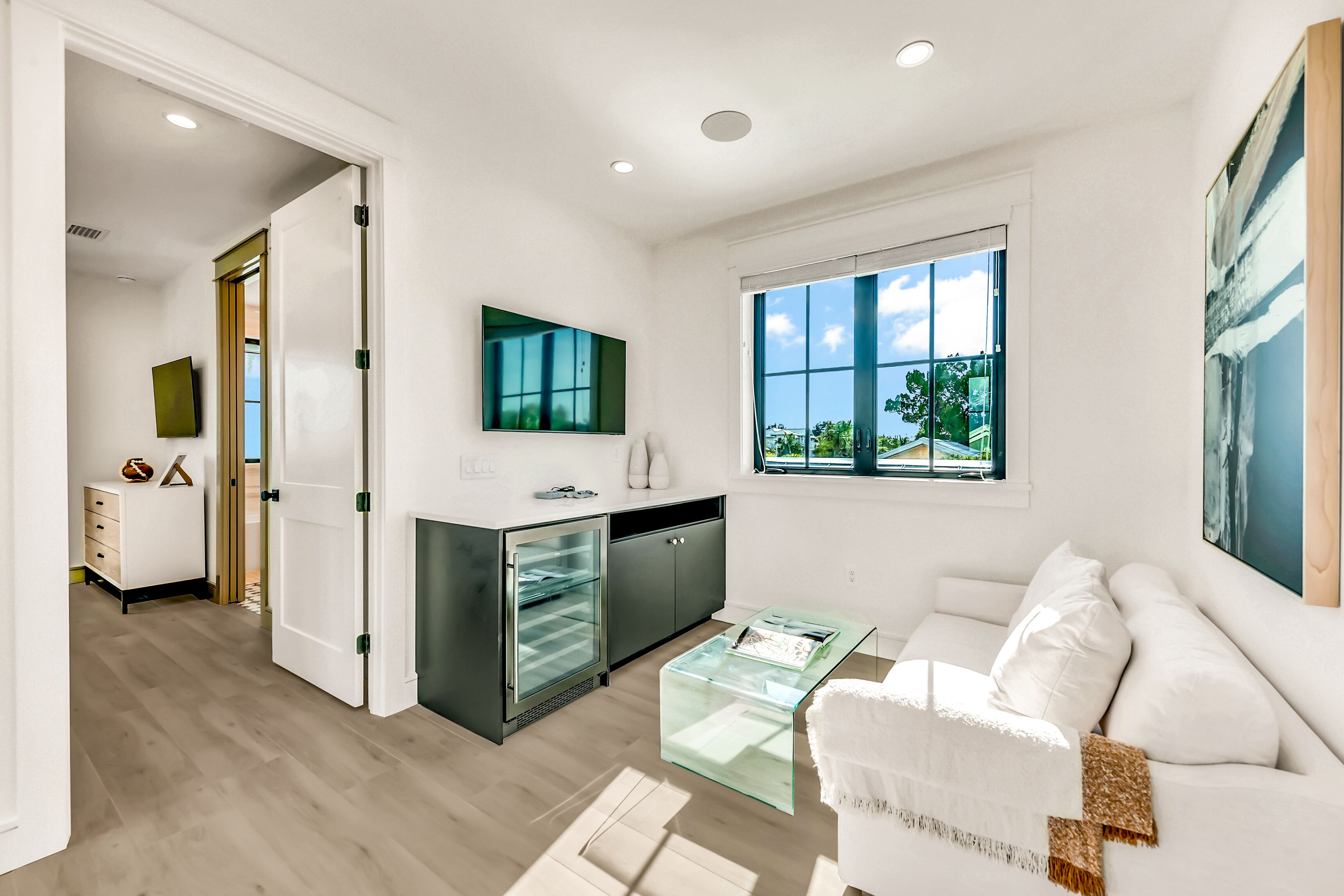 Una cocina moderna con un refrigerador empotrado, un comedor con mesa de vidrio y un sofá blanco.