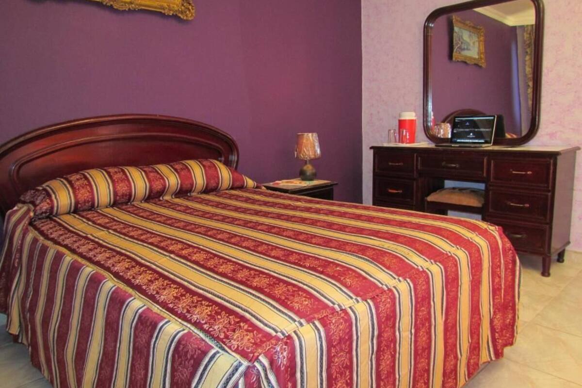 A room with a bed, a dresser, a mirror, and a lamp.