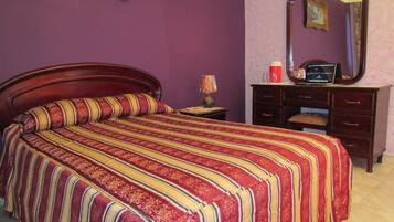 Una habitación con cama, cómoda, espejo y lámpara.