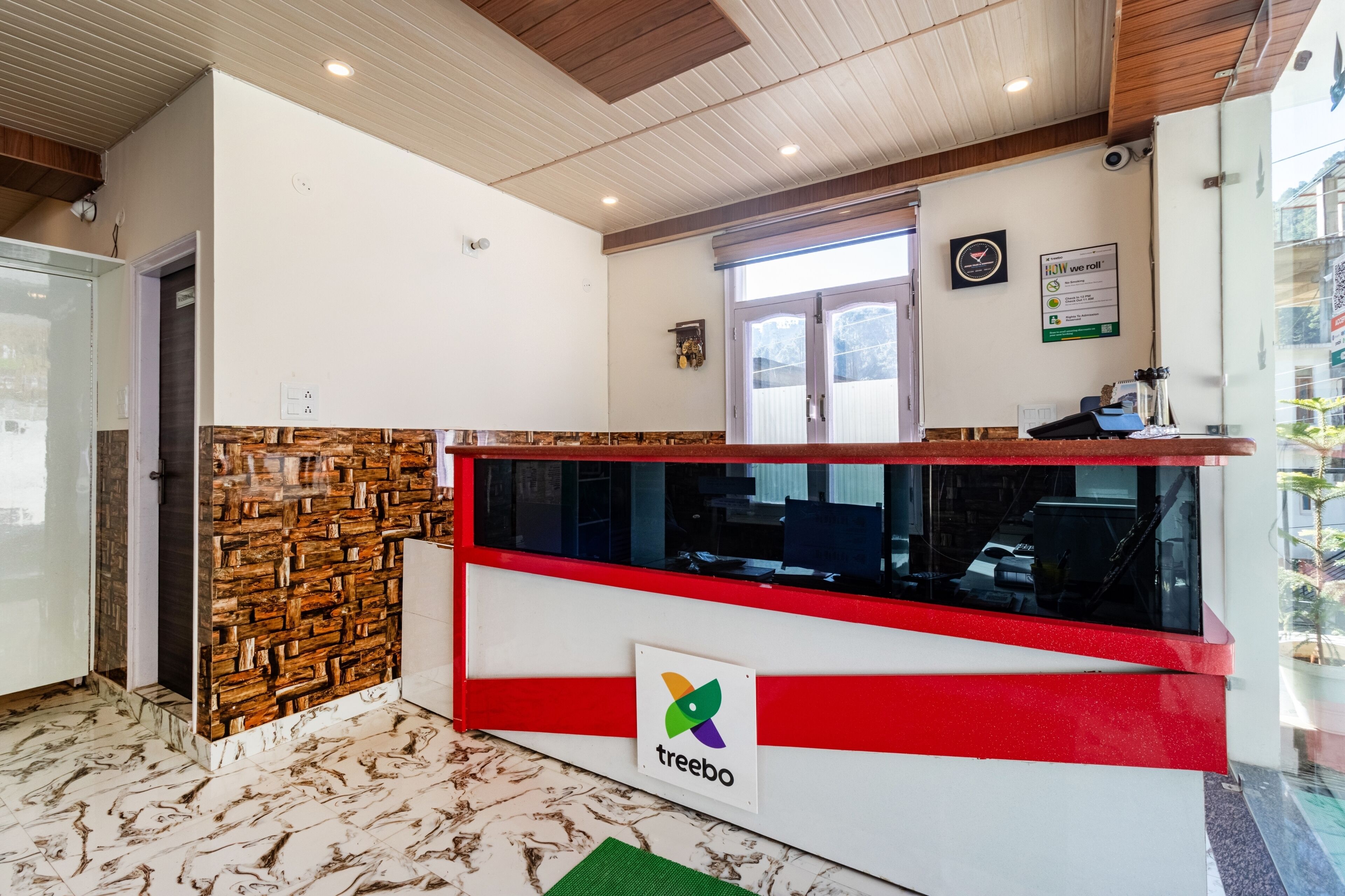 A reception desk with a logo, a stone wall, and a window.