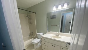 Une salle de bain avec des toilettes, un lavabo et une douche.