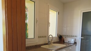 A kitchen with a double sink, wooden cabinets, and a window. - Fantastic views , sun and relax at Altea Hills Charming house Costa Blanca (Altea Hills)