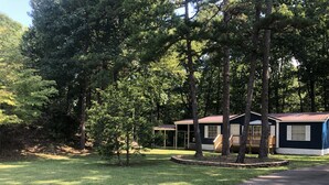 A row of cabins with a covered porch, surrounded by trees and a grassy area. - The Prefect Retreat! (Counce)