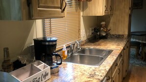 A kitchen with wooden cabinets, a granite countertop, a coffee maker, and a sink. - The Prefect Retreat! (Counce)