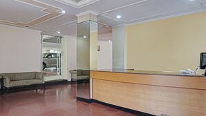 Un'area di accoglienza con un bancone in legno, due divani a fantasia e una porta in vetro che dà sull'esterno.