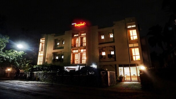 Un hotel con insegna al neon, diverse finestre e un ingresso sorvegliato da cancello.