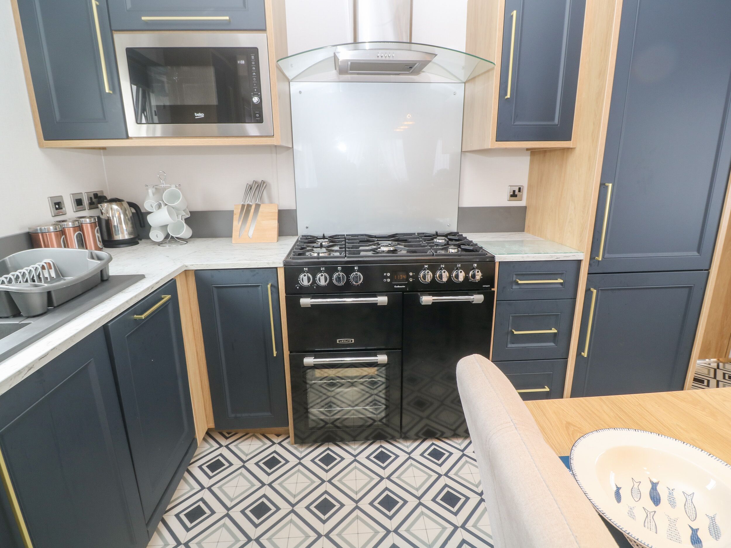 Een compacte keuken met een gasfornuis, oven, magnetron en roestvrijstalen apparatuur.