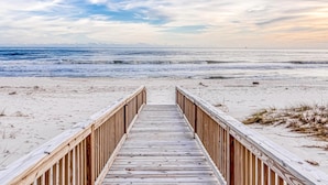 A wooden boardwalk leading to a beach with a clear sky. - Beachfront in Morgantown (Gulf Shores)