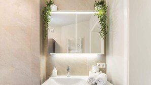 Un bagno con un lavandino bianco, uno specchio e un porta asciugamani.