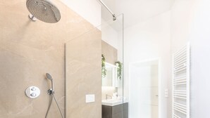 A modern bathroom with a glass shower enclosure, a toilet, a sink, and a mirror. - Stockholm Style Design in Limpertsberg (Luxembourg)