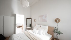 A bedroom with a bed, a wardrobe, a mirror, and a wall-mounted light fixture. - Stockholm Style Design in Limpertsberg (Luxembourg)
