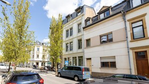 A street view with parked cars, a blue van, and buildings with balconies and windows. - Stockholm Style Design in Limpertsberg (Luxembourg)