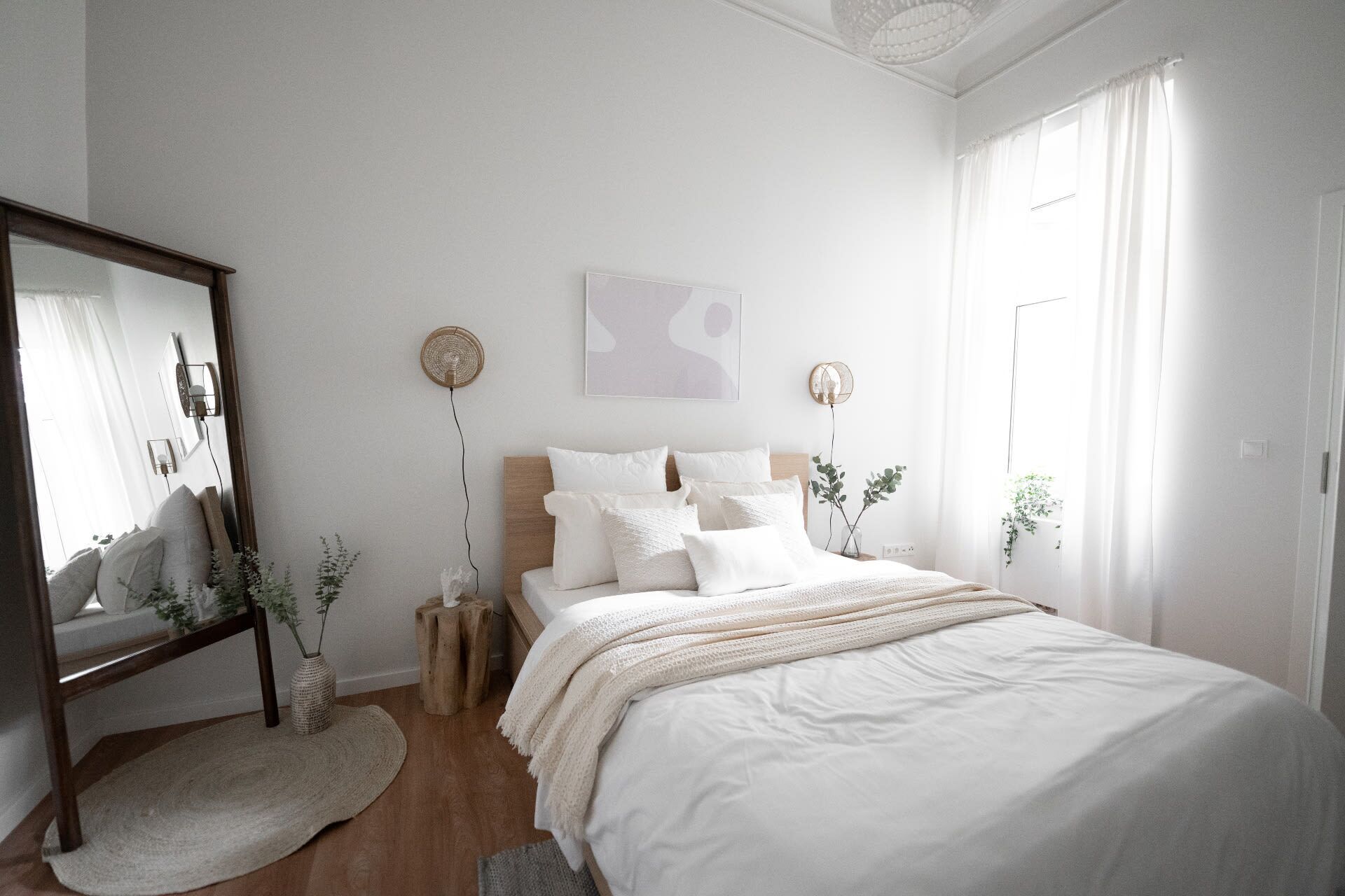 Un dormitorio con cama, mesitas de noche, espejo y ventilador de pared.