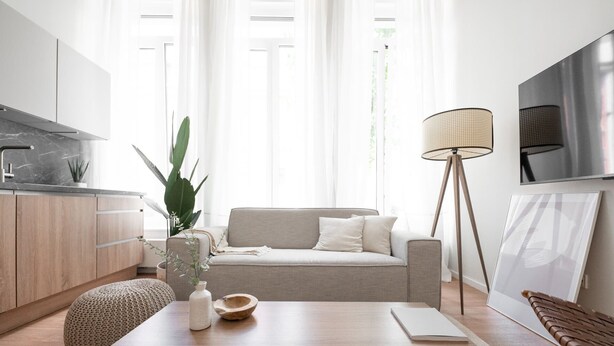 A modern living space with a sofa, a coffee table, a floor lamp, and a kitchen area. - Stockholm Style Design in Limpertsberg (Luxembourg)