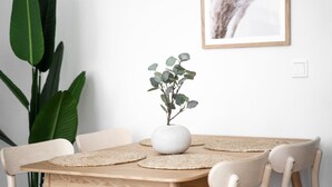 A dining table with a white vase and a plant, surrounded by chairs and placemats. - Stockholm Style Design in Limpertsberg (Luxembourg)