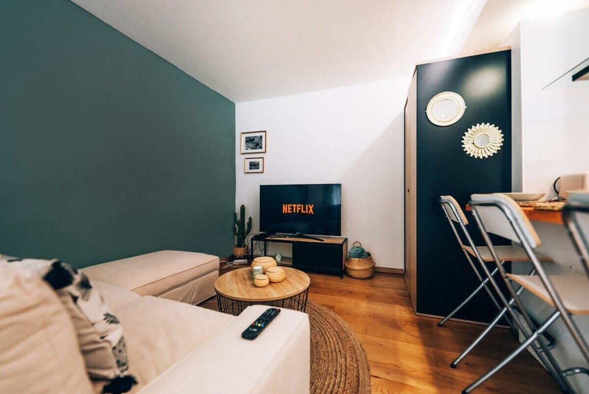 Een moderne woonkamer met een bank, een salontafel, een televisie en een eethoek met stoelen en een tafel.