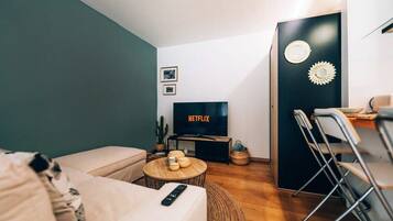 Een moderne woonkamer met een bank, een salontafel, een televisie en een eethoek met stoelen en een tafel.