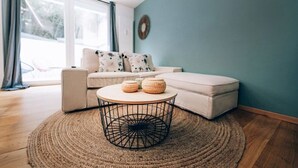 Een moderne woonkamer met een ronde salontafel, een bank en een groot raam met gordijnen.