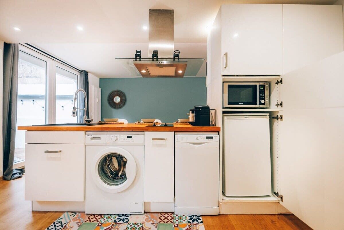 A compact kitchen with a washing machine, microwave, and a small refrigerator.