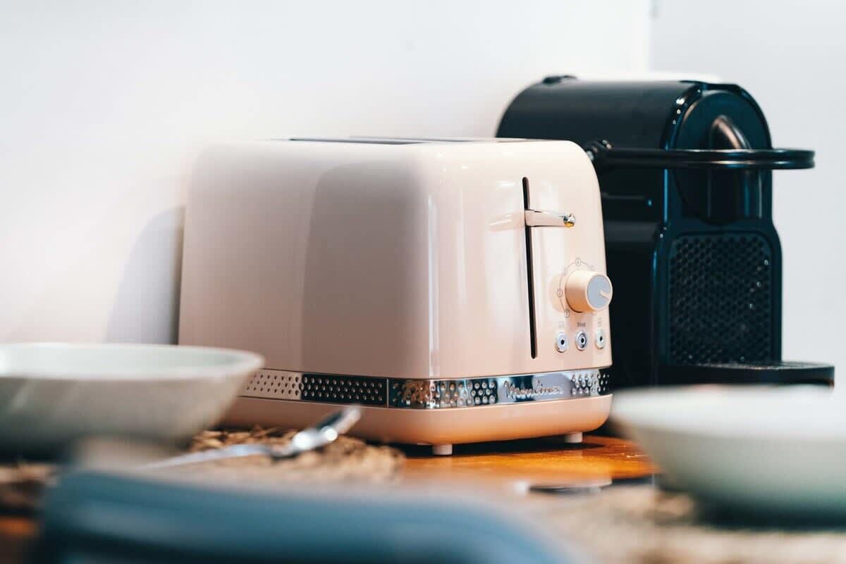Eine Küche mit einem wei ßen und schwarzen Toaster, einer Kaffeemaschine und einer Schüssel auf der Arbeitsfläche.