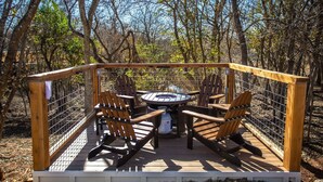 Eine Terrasse mit einem runden Tisch und vier Adirondack-Stühlen, umgeben von einem Holzzaun.