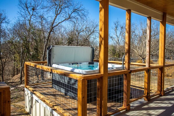 Relax in a hot tub on an outdoor deck with a secure fence and scenic views.