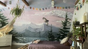 A bedroom with a mountain mural, a hammock, a bed with a purple bedspread, and a wooden pallet. - The Riverfront Retreat- 27 minutes to Sugarloaf! (New Portland)