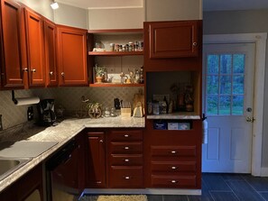 Una cocina con armarios de madera, una encimera con distintos objetos y una puerta con ventana.
