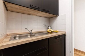 Una cocina con pileta de acero inoxidable, encimera de madera y muebles bajos negros.
