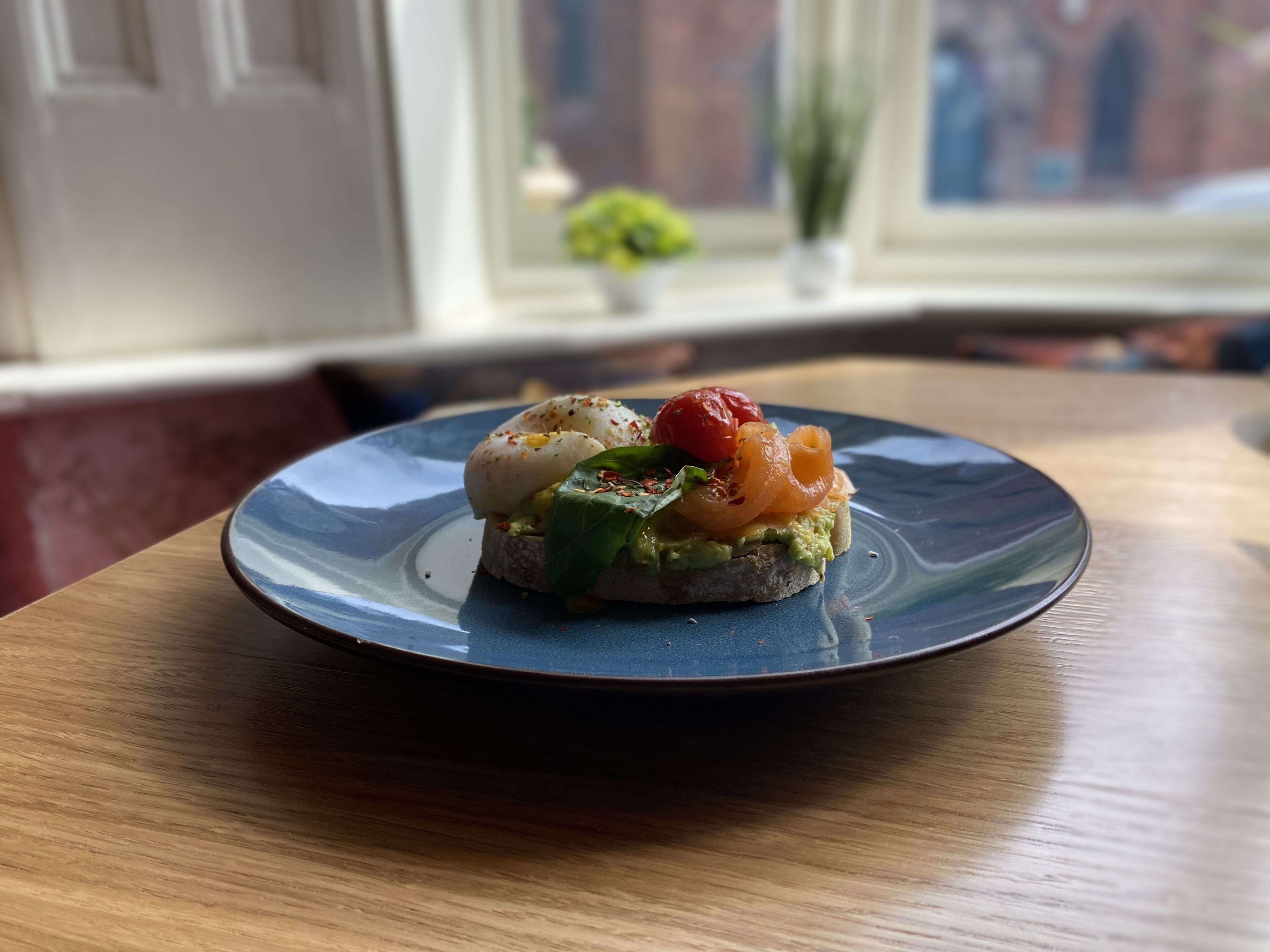 Une assiette avec un sandwich posé sur une table en bois.
