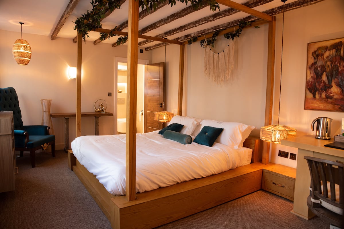 Une chambre à coucher avec un lit à baldaquin, des tables de chevet, un bureau et une chaise.