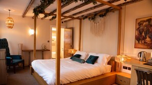 Un dormitorio con cama con dosel, mesitas de noche, un escritorio y una silla.