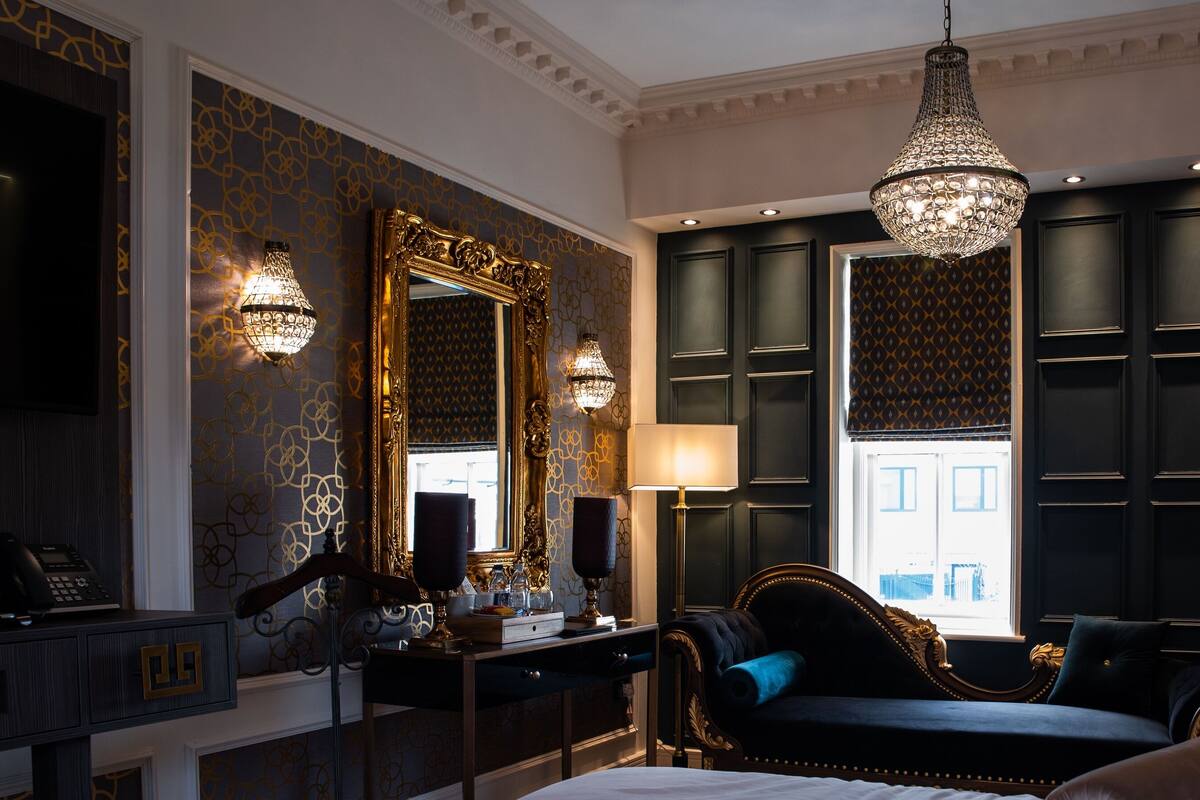 Une chambre à coucher luxueuse, dotée d’un grand lit, d’une commode, d’une coiffeuse avec un miroir et d’un lustre.