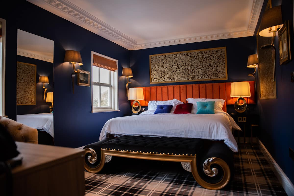 Une chambre à coucher avec un grand lit, deux tables de chevet, une fenêtre et une tête de lit.