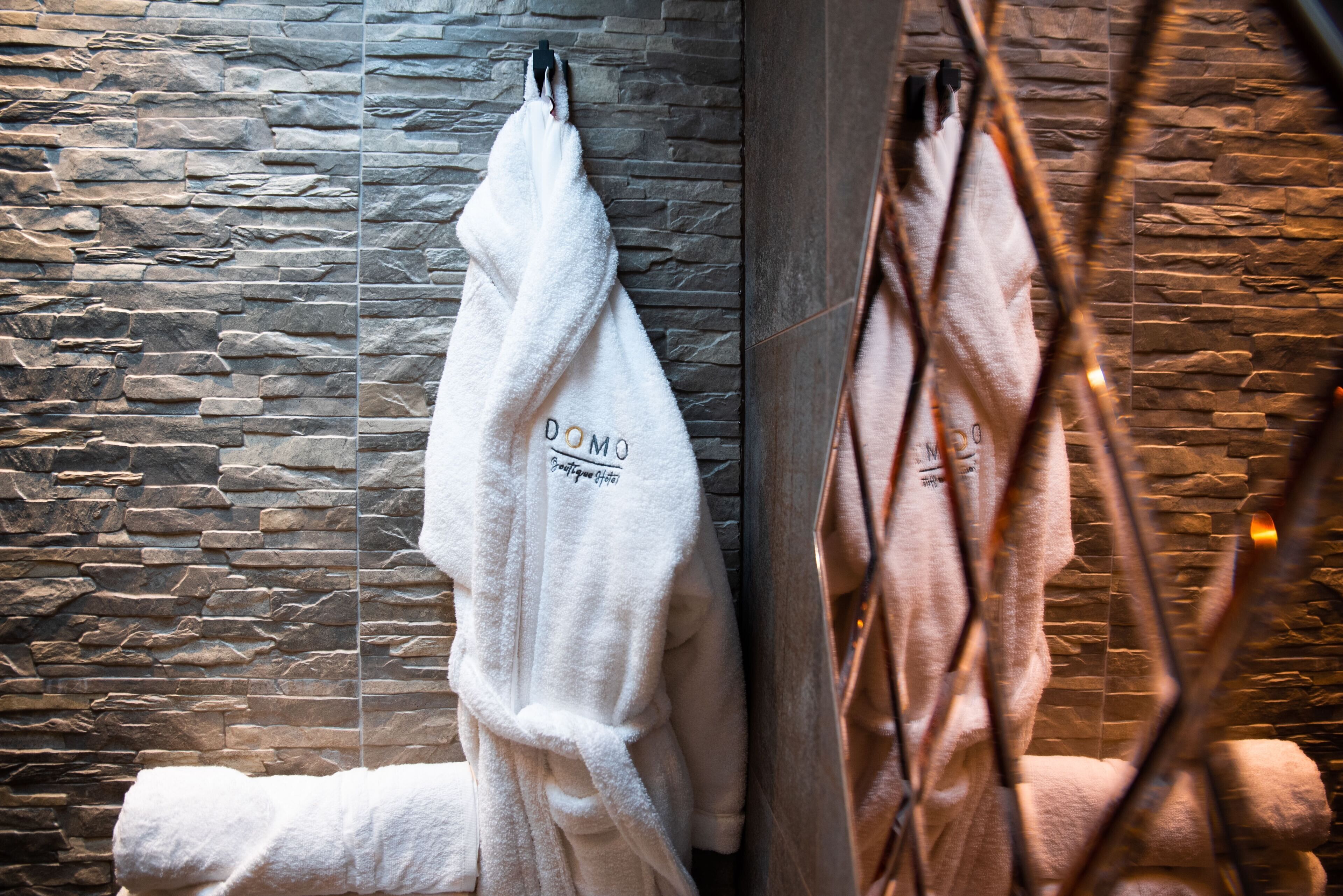 A white towel with "DOMO" text hanging on a stone wall.