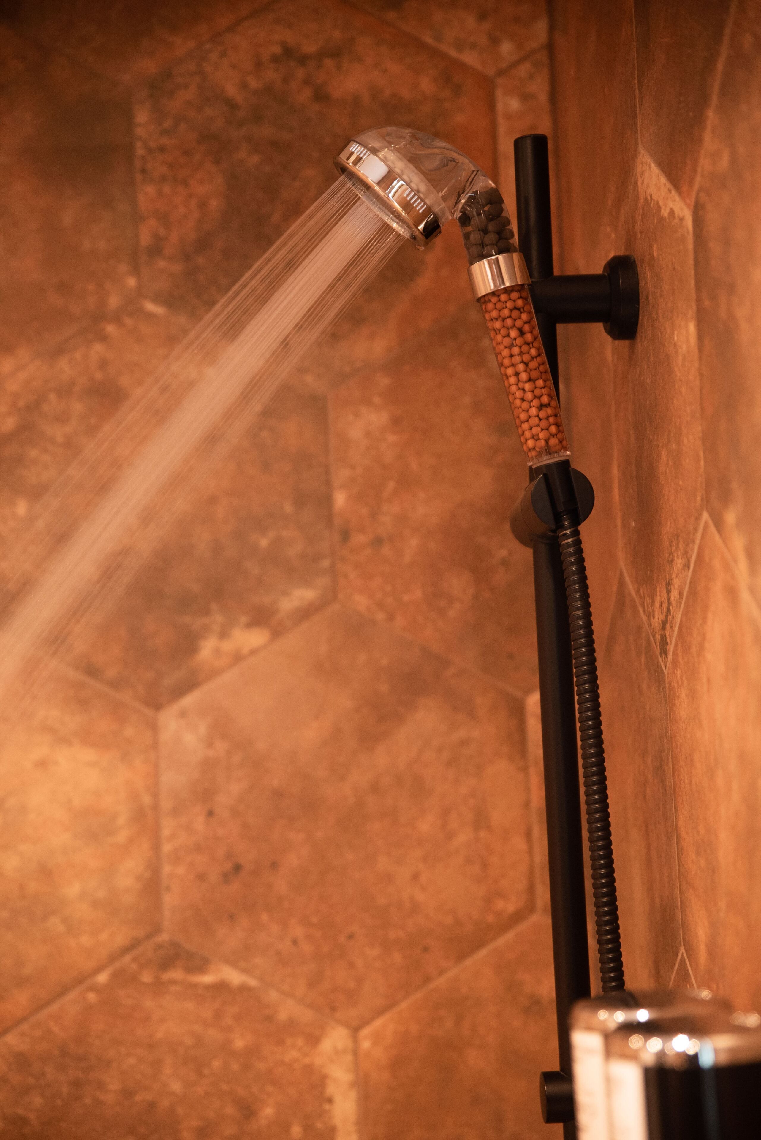 Une douche dotée d’un bec verseur transparent et d’une poignée texturée.