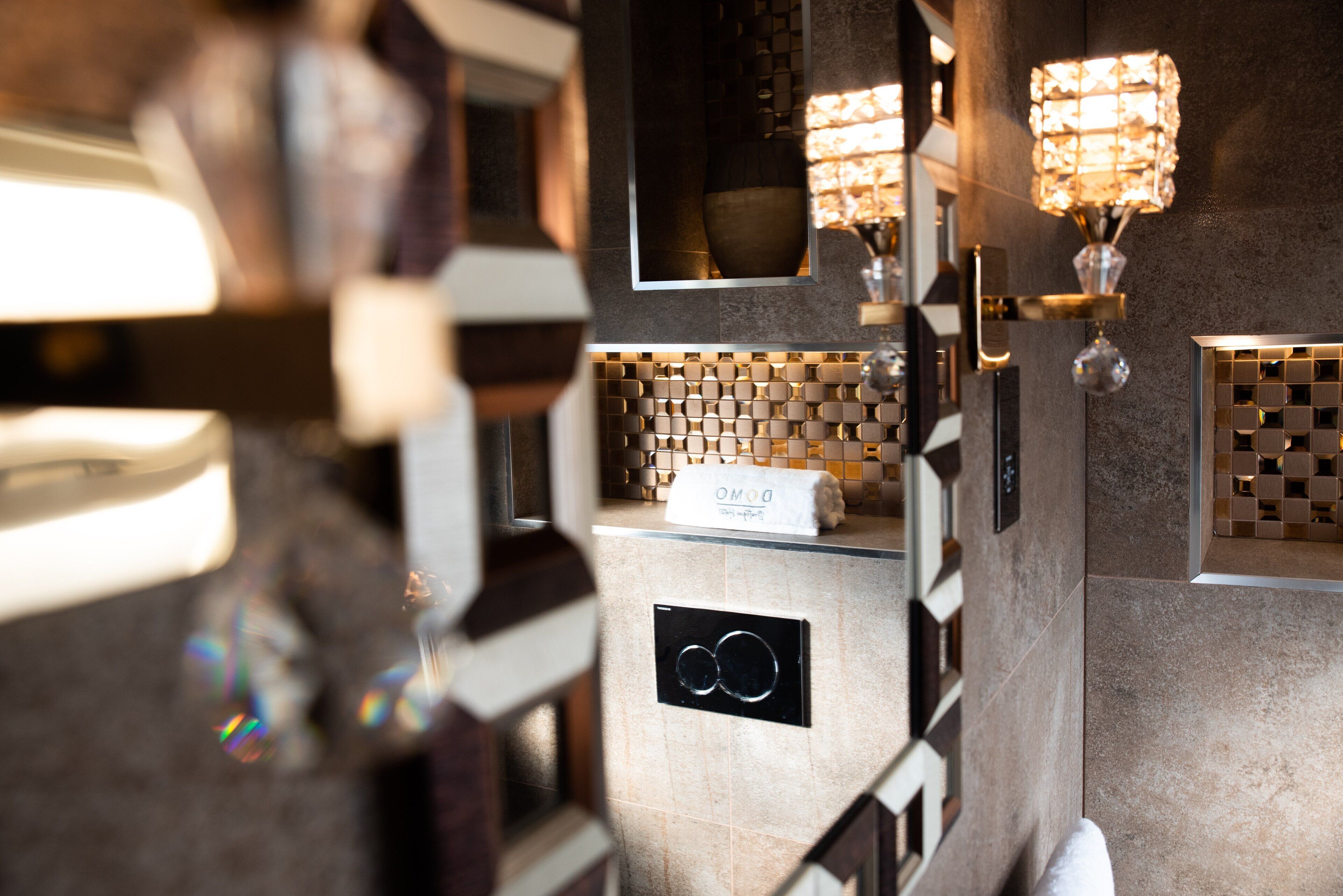 A modern bathroom with a tiled backsplash, a towel rack, and two wall-mounted light fixtures.