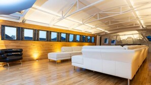 A spacious, modern interior with a wooden wall, large windows, and a white sectional sofa.
