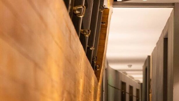 A corridor with wooden flooring and metal railings.