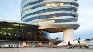A modern airport terminal with a distinctive curved architecture and a glass facade. - Amazing Luxe Home w/ AirCon & HUGE Yard | FirePit (Edmonton)