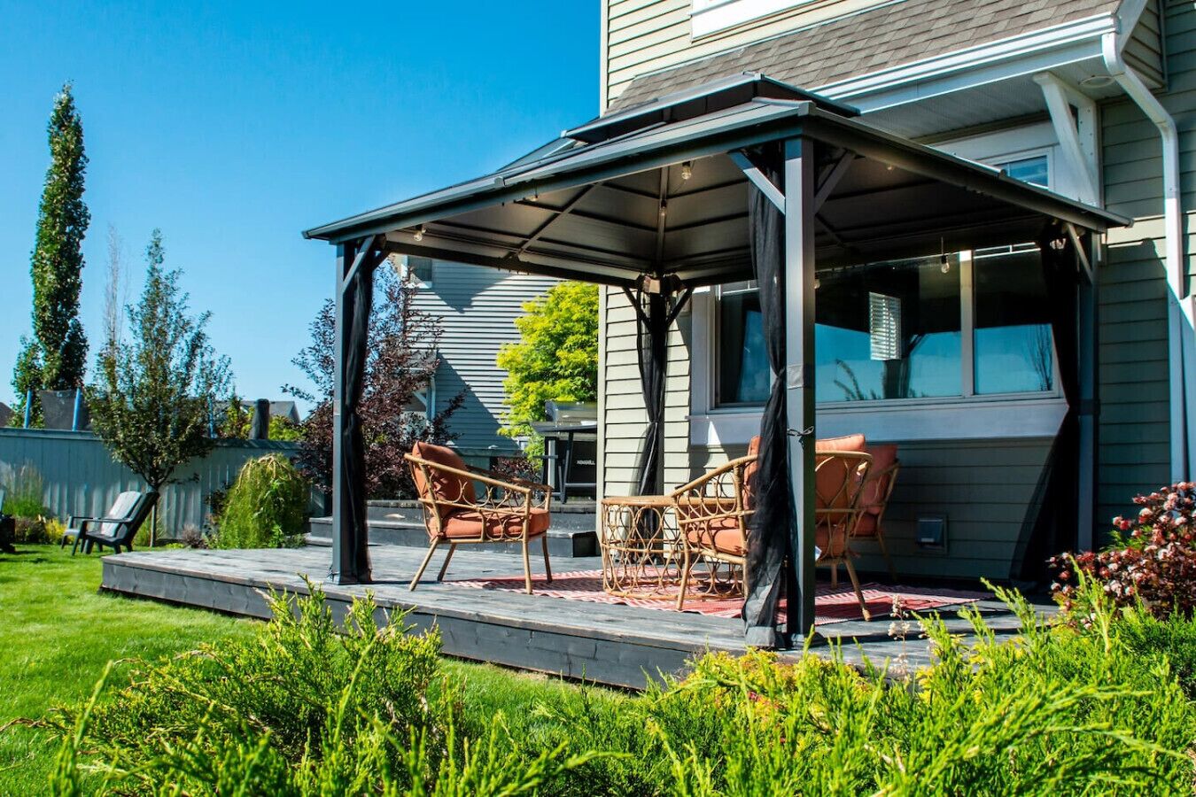 A covered patio with outdoor furniture, a small pool, and a house in the background.