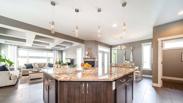 A spacious kitchen with a large island, dark wood cabinetry, and pendant lighting. - Amazing Luxe Home w/ AirCon & HUGE Yard | FirePit (Edmonton)